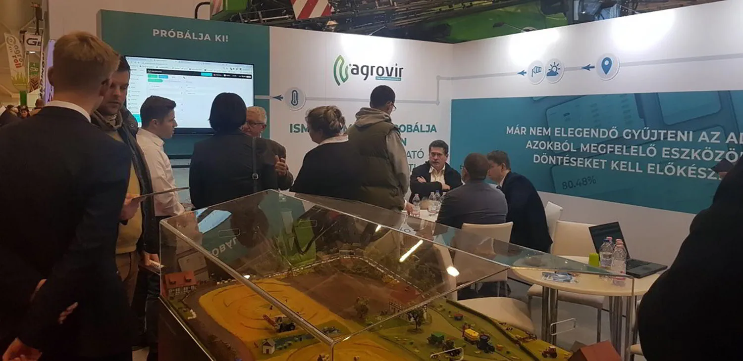 Látogatók az AgroVIR standján a 2020-as AgroMashEXPO-n, előtérben egy gazdaságmakett
