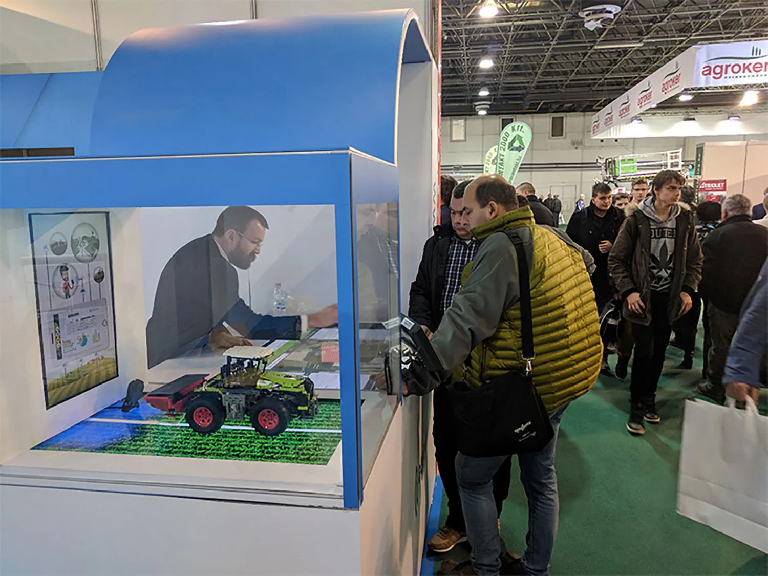 Látogatók az AgroVIR standján az AGROmashEXPO 2018-on, a vitrinben legóból épített traktor