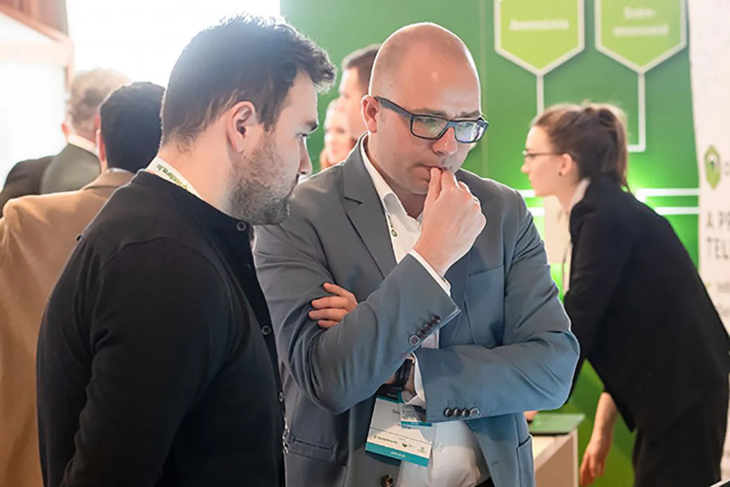 Két férfi elmélyülten figyel egy agrárszakmai konferencia kiállítói standjánál